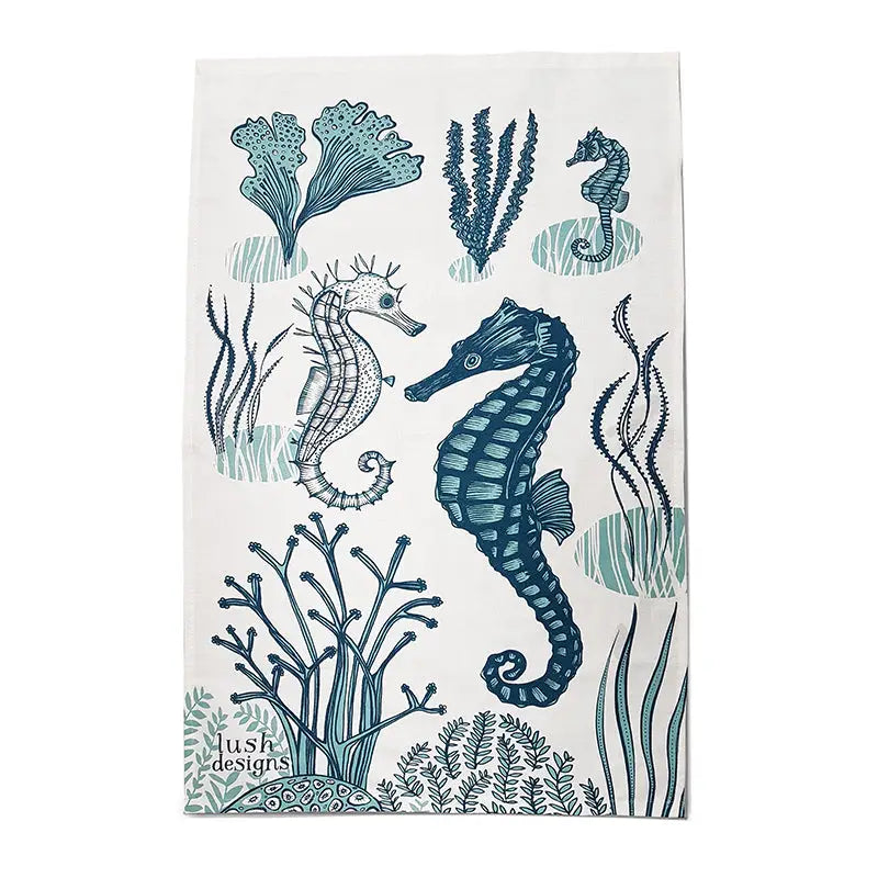 a tea towel with an artist depiction of two sea horses under the sea with coral 