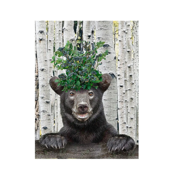 a colourful tea towel with a black bear wearing a bluberry head dress. on a birch tree background 