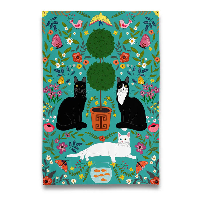 a tea towel with 3 cats and a topiary plant on a green background 