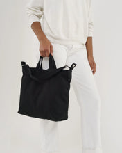 Load image into Gallery viewer, a person holding a black canvas baggu dusck bag 
