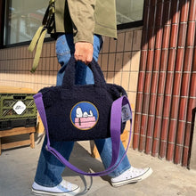Load image into Gallery viewer, phot of a person carrying a navy blue fuzzy tote bag with an emblem of snoopy from cartoon peanuts on it 
