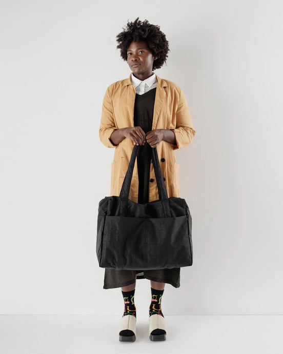 a person holding a large black tote bag made by baggu