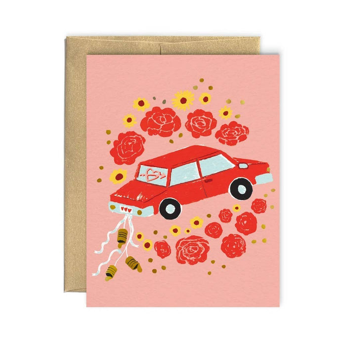 a red car with trails of cans and flowers all around