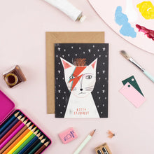 Load image into Gallery viewer, a greeting card with illustration of a cat looking like david bowie character ziggy stardust with red flash makeup on. text kitty stardust