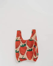 Load image into Gallery viewer, a colour photo of a small baby sized baggu reusable bag with large red  strawberries on it , bag is soft peach colour 
