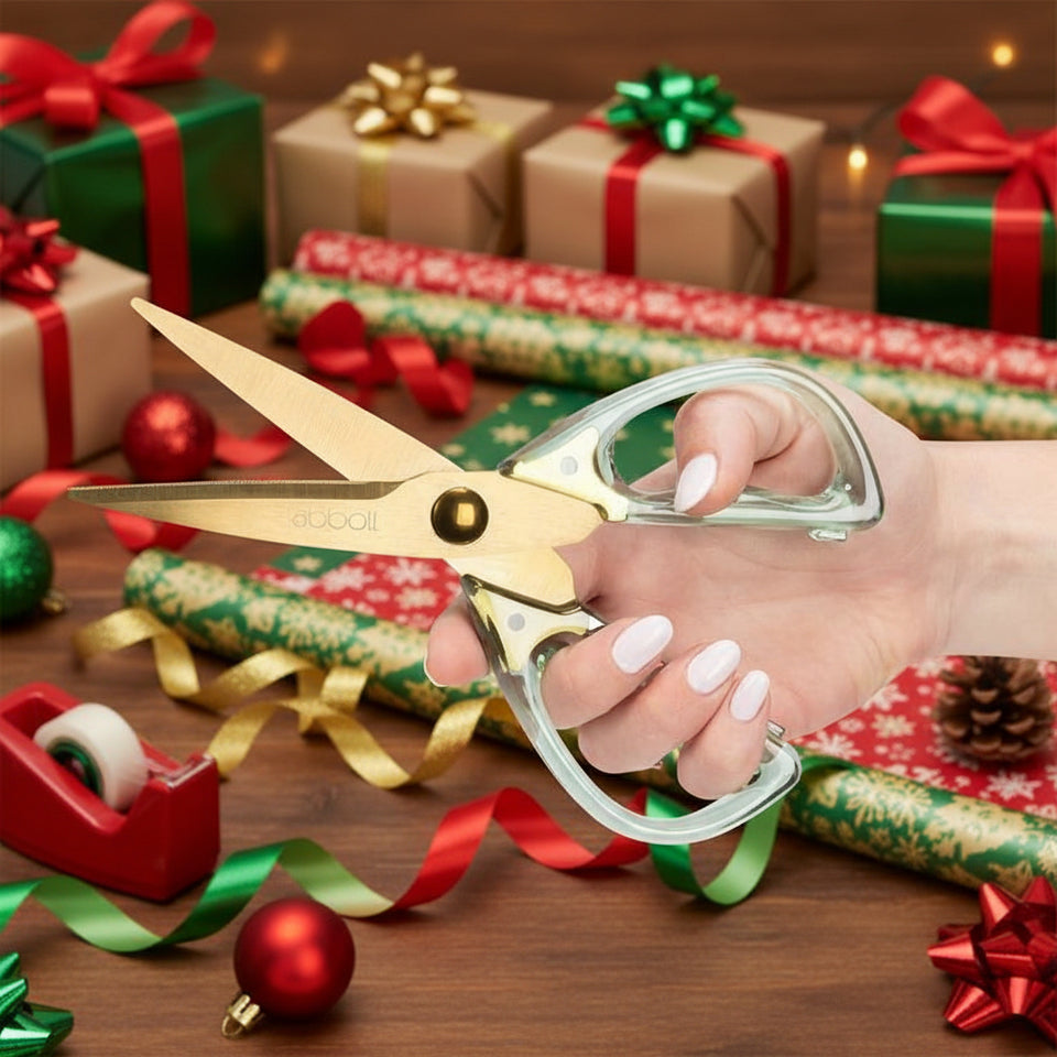 GREEN SCISSORS WITH FESTIVE RIBBONS AND WRAP IN BACKGROUND
