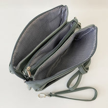Load image into Gallery viewer, the inside of a handbag showing the pockets and zippers and striped lining 

