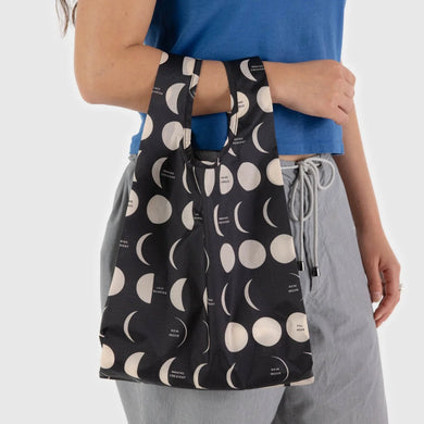 a person holding a baggu brand reusable shopping bag in a idnight moon motif