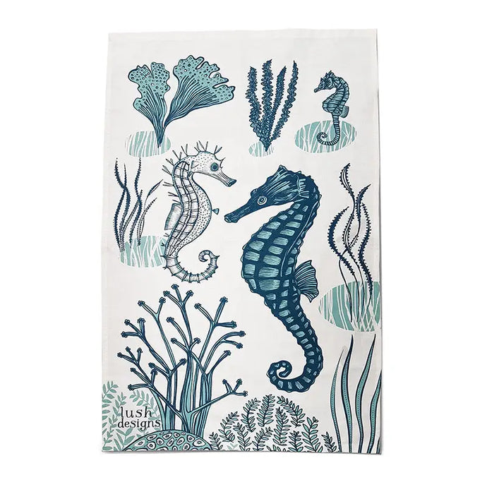a tea towel with an artist depiction of two sea horses under the sea with coral 