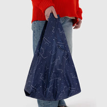 Load image into Gallery viewer, a person holding a baggu brand reusable bag in a out space stars motif 
