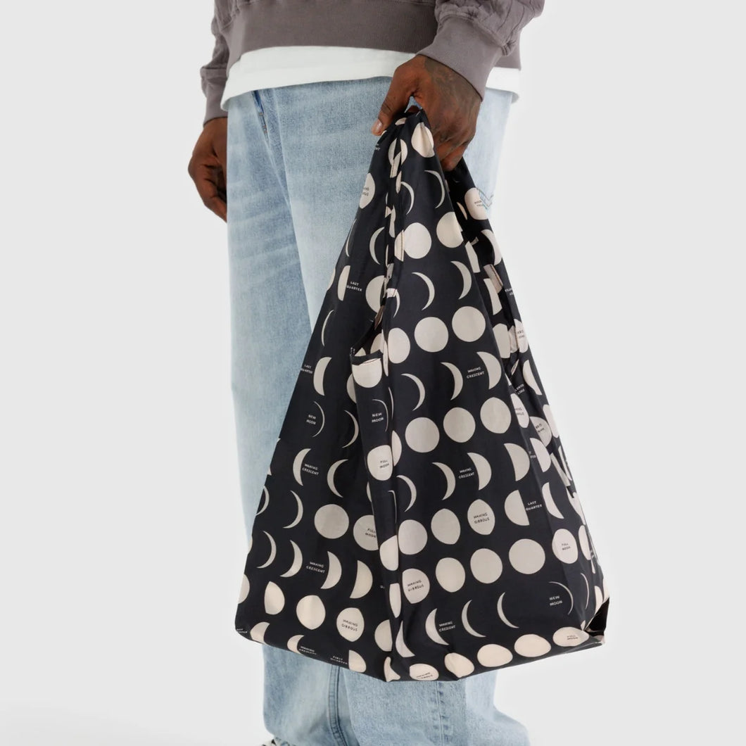 a person holding a baggu brand reusable bag in black with moons and half moons motif 