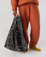 画像をギャラリービューアに読み込む, a person holding a baggu reusable shopping bag in a motif with stars and fish 

