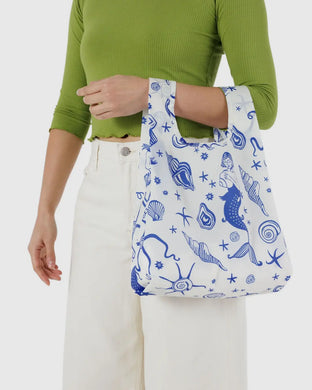a person holding a baggu brand reusable bag in a white colour with blue motif of under the sea creatures 