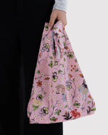 Floral-patterned pink bag held by a person against a white background