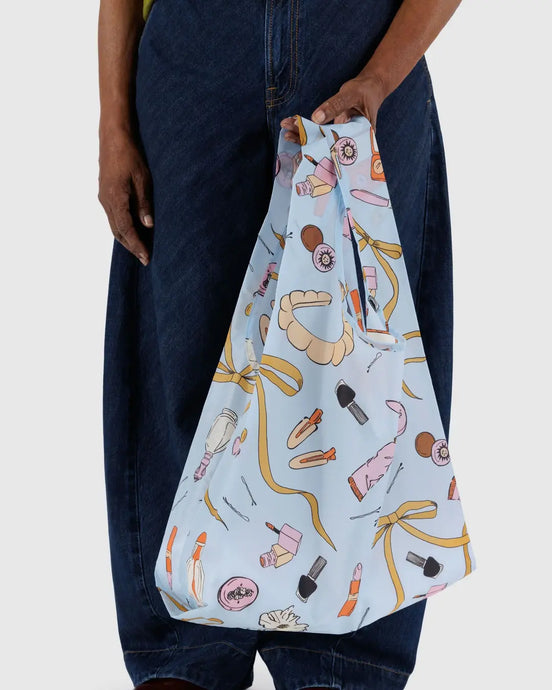 a person holding a baggu reusable bag with the get ready with me motif 