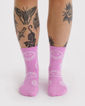 Load image into Gallery viewer, Pink socks with smiley face patterns worn by a person with tattoos on a white background
