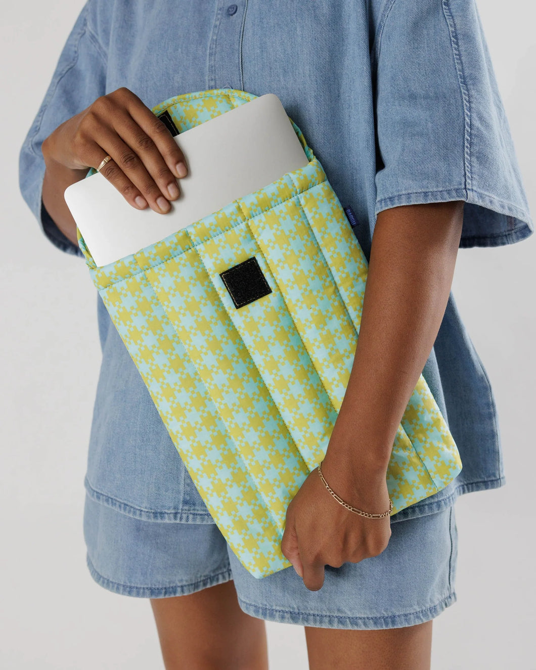 a person taking a laptop out of a pixel gingham mint colour baggu laptop sleeve