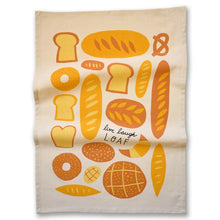 Load image into Gallery viewer, A cream-colored kitchen tea towel featuring a playful illustration of various breads, loaves, and pastries in shades of yellow, orange, and brown, with the text 'live laugh LOAF' printed in black script.
