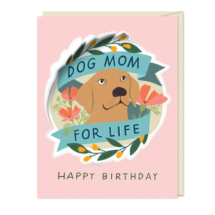 an illustration of a dogs face inside a laurel wreth that says dog mom for life on a soft pink background