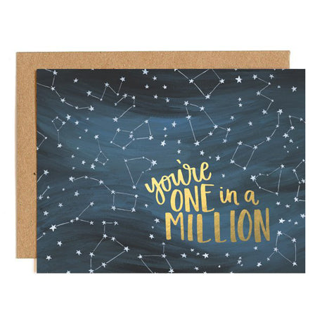 an illustration of the galaxy or stars connected with dots on a dark noght sky with scipt you're one n a million of gold with kraft envelope 