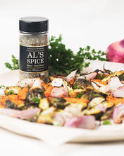 Load image into Gallery viewer, a bottle of Al&#39;s Spice with a black label and black top beside a plate of what looks like roasted vegetables
