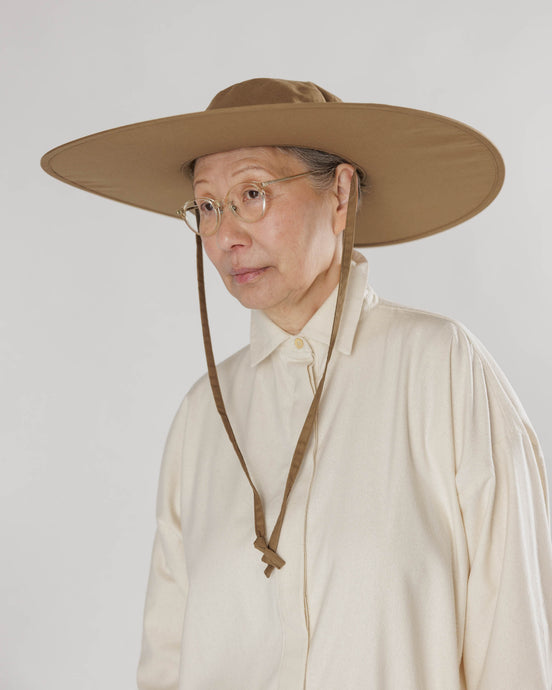 a person wearing a baggu packable sunhat in the tamarind pattern. creamy brown 