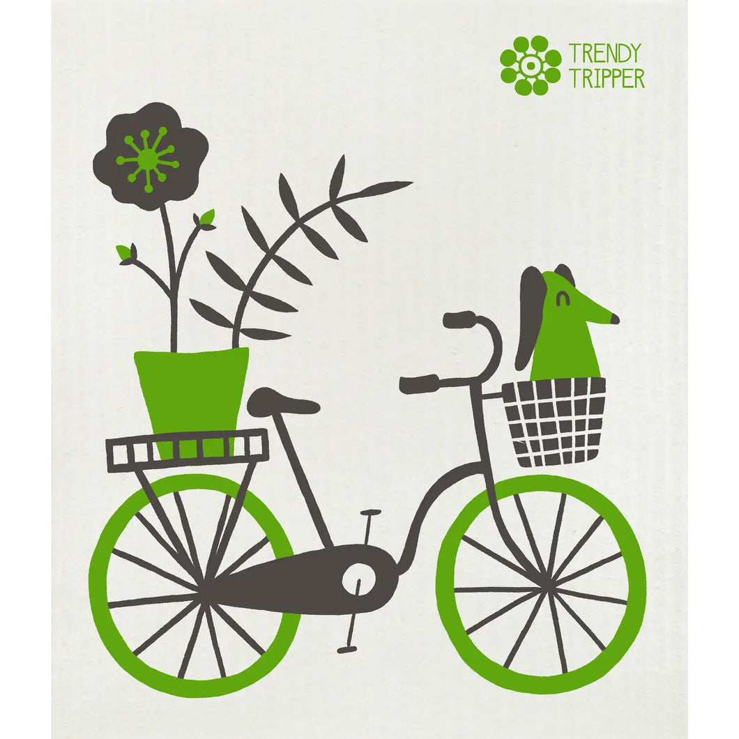a Swedish dishcloth with an image of a green bike and a dog riding in the the basket with a big plower pot on the back 
