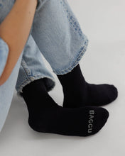 Load image into Gallery viewer, a pesons feet wearing black socks by baggu
