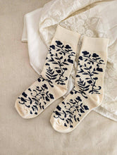 Load image into Gallery viewer, a colour photo of a pair of creme coloured socks with black flowers on them
