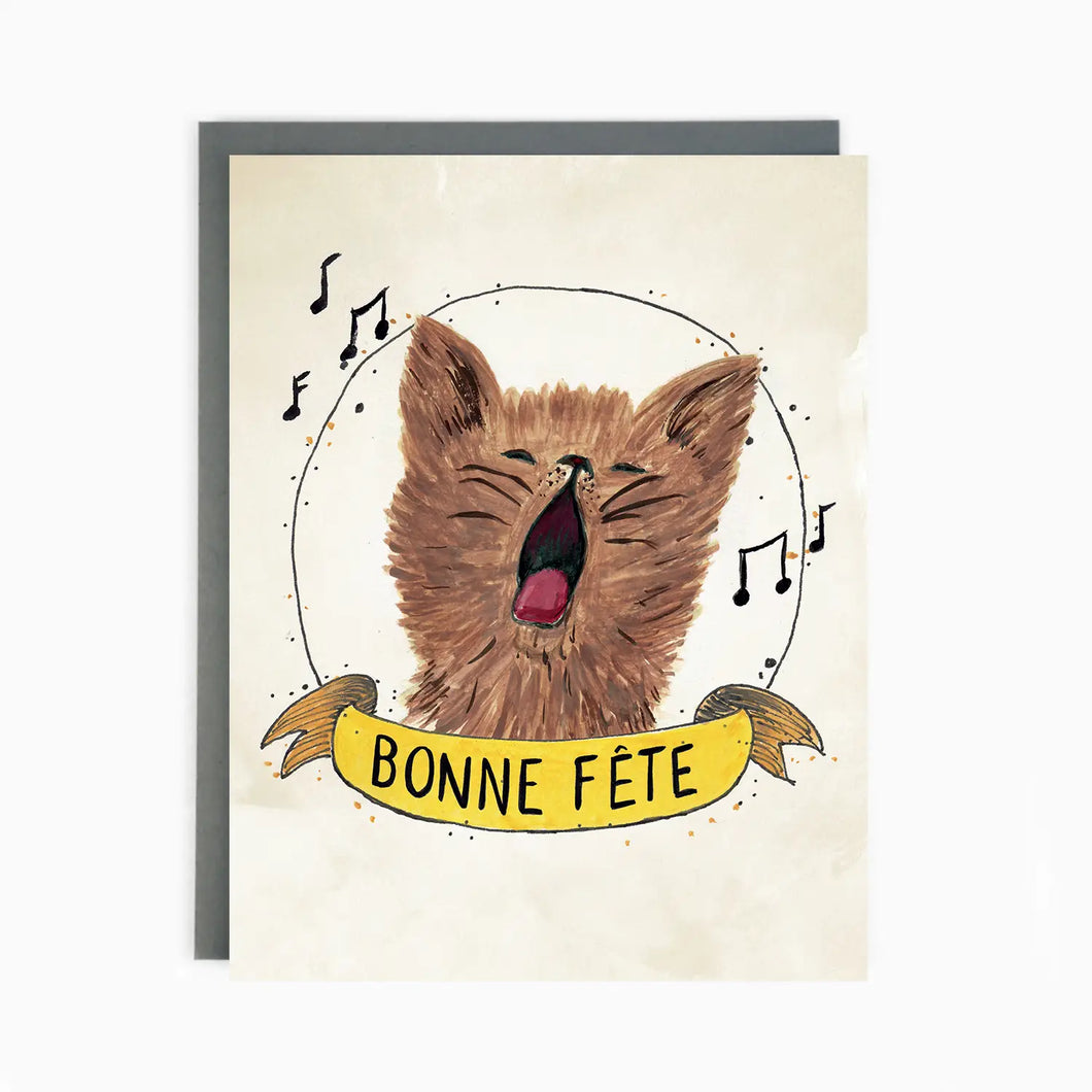 a greeting card with an illustration of a cat singing musical notes around text bonne fete