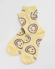 Load image into Gallery viewer, a piar of baggu socks that are yellow butter coloured with purple happy or smiley faces all over them
