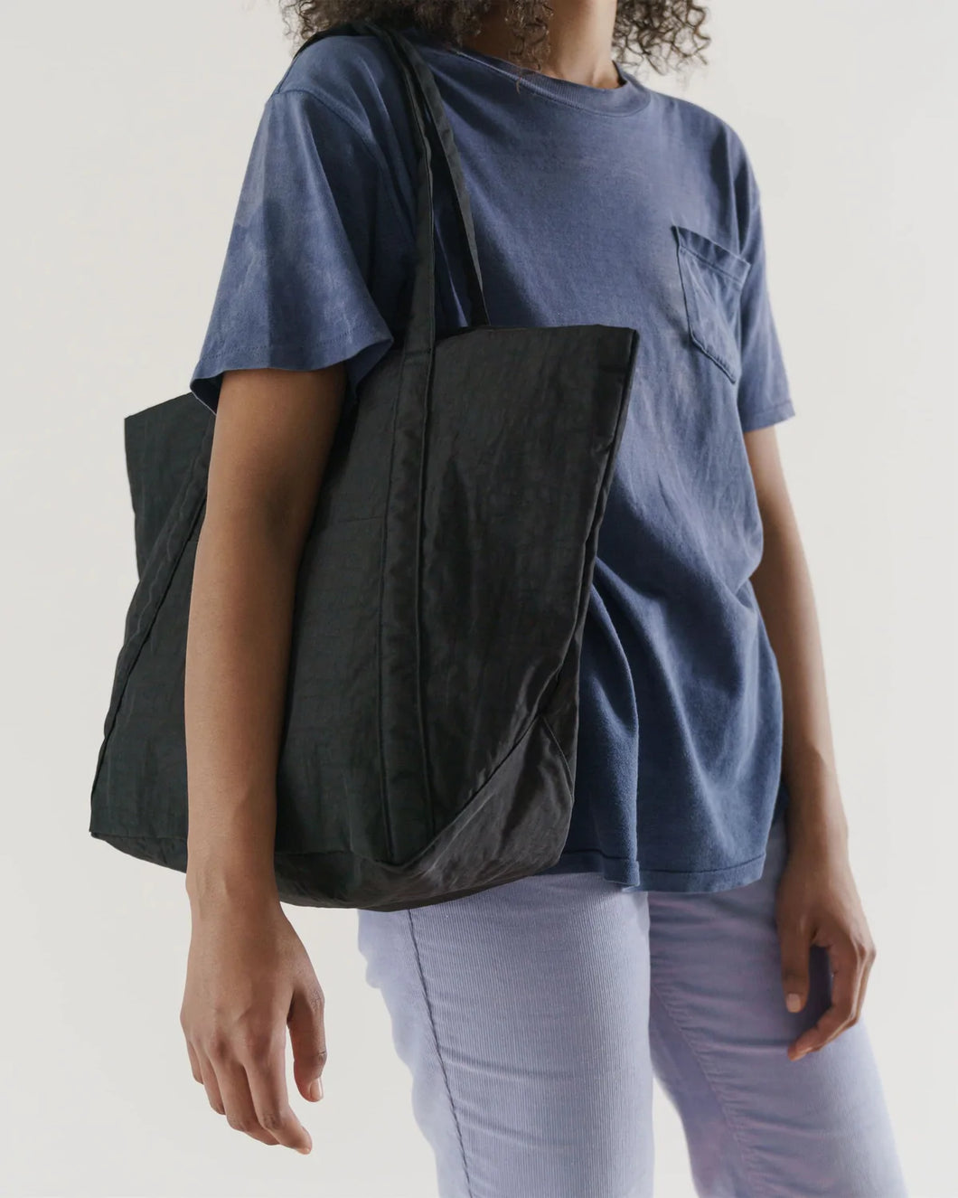 a person carrying a baggu cloud travel bag in a black colour 