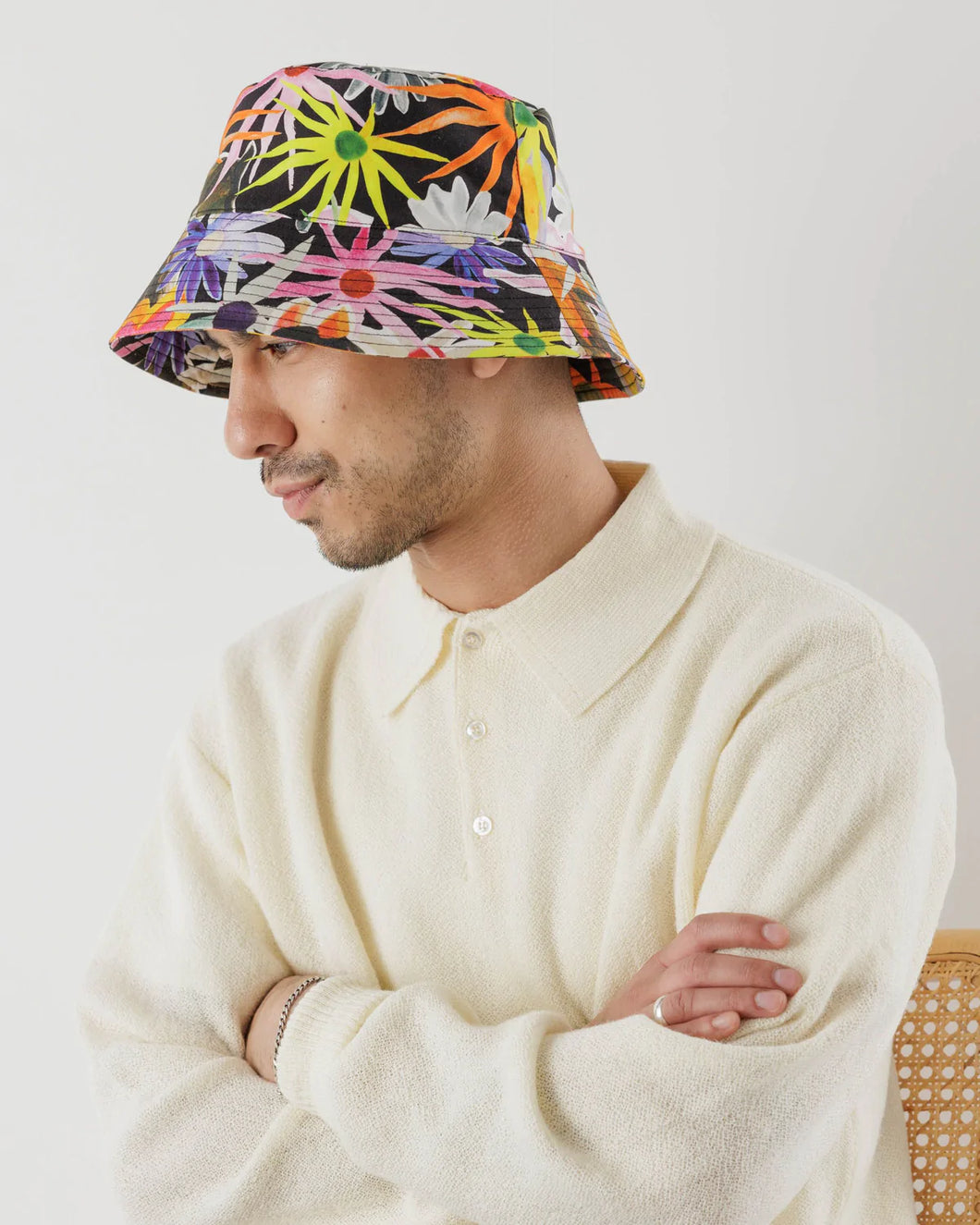 a person wearing a baggu bucket hat that is very vibrant and colourful  featuring large flowers and horses 
