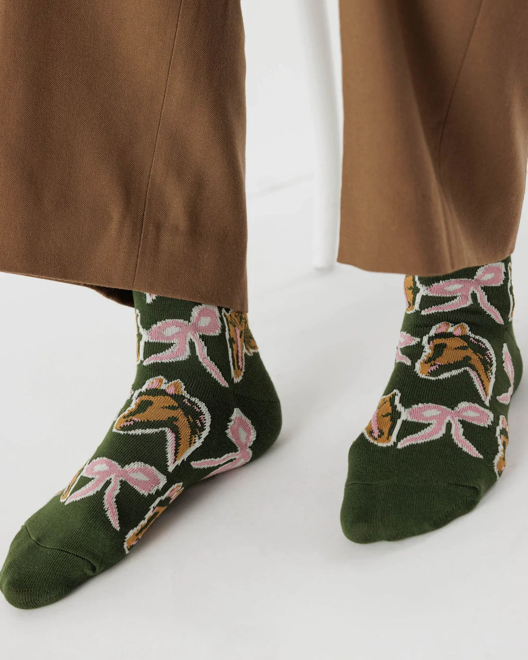 a pair of buugu jessica williams socks in green with horses and bows on them 