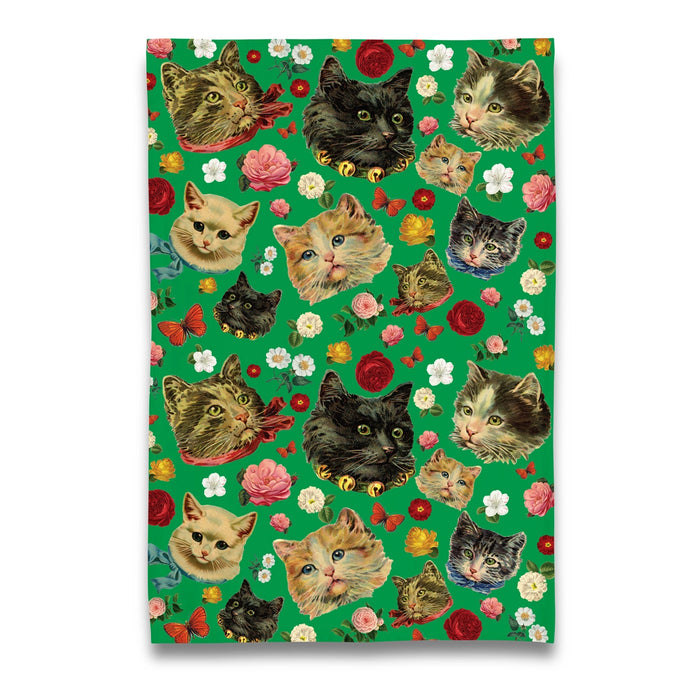 a tea towel with faces of 1950' cats and flowers all over on a green background very retro