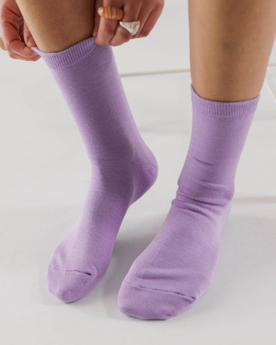 colour photo of a persons feet wearing lavender colour socks