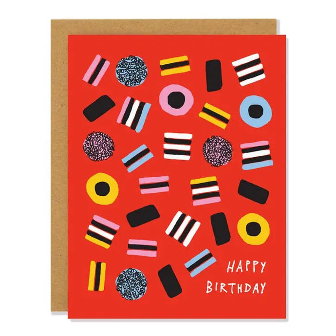 a red coloured greeting card covered in liquorise alsort candies . text happy birthday 