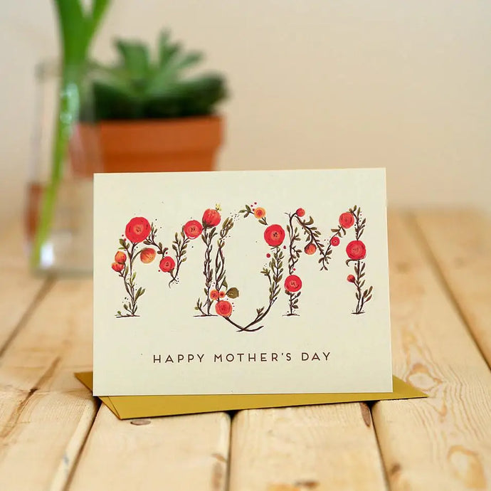a greeting card with an illustration of the text mom written in small flowers. remaining text says happy mothers day .xt 