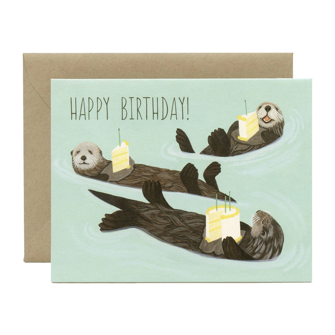 colour illustration of three otters floating on their backs carrying a piece of birthday cake. text happy birthday 