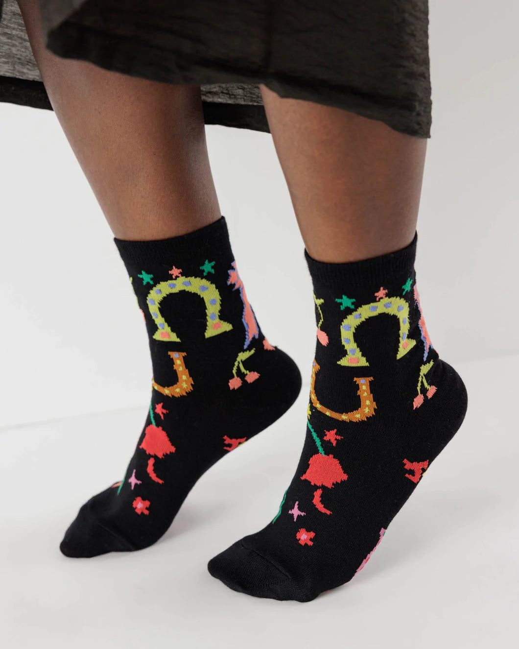 a person wearing black baggu rodeo socks with horseshoes and cherries s on them 