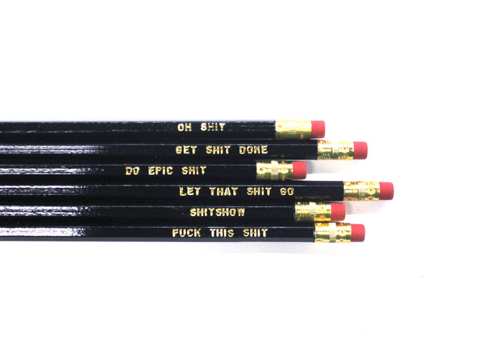 a set of six black pencils with assorted shits written on each one in gold text