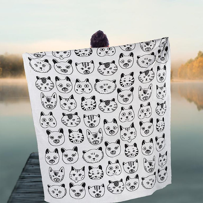 a person holding open the white with black faced kitties large throw blanket.