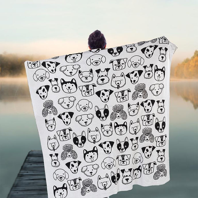 a person holding a blanket throw with black and white dog faces on it 