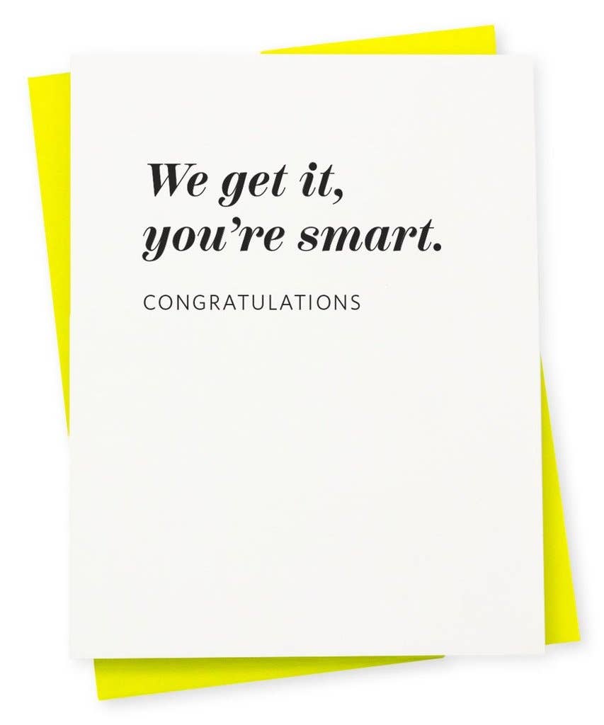 a white greeting card with black script we get it, you're smart. congratulations, paired with a bright yellow envelope 