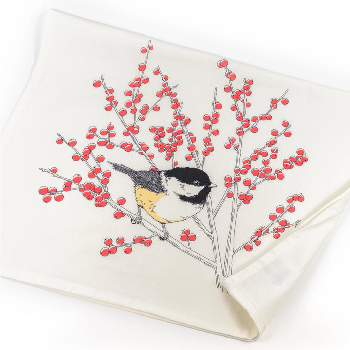 a white tea towel with a black capped chickadee bird sitting on red berry branches 