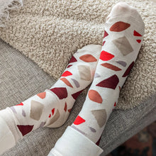 Load image into Gallery viewer, photo of a pair of socks being worn by a person. shapes of terrazzo in reds and greys and browns 
