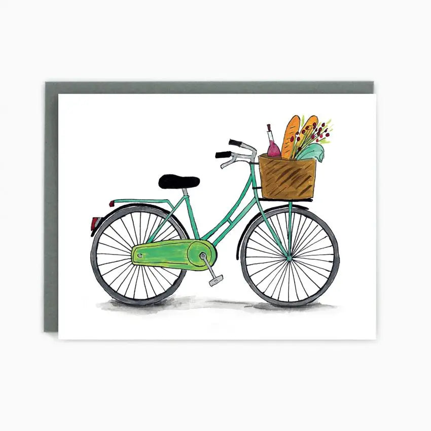 a greeting card with an illustration of a bicycle with a wicker carrying basket filled with baguette wine and flowers 