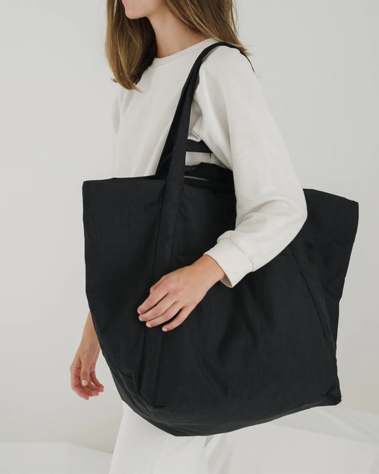 a person carrying a large cloud baggu black coloured travel bag 