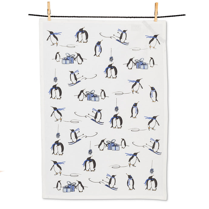 colour photo of a tea towel covered in penguins skating and skiing with a sprinkle of little gift boxes thru out 